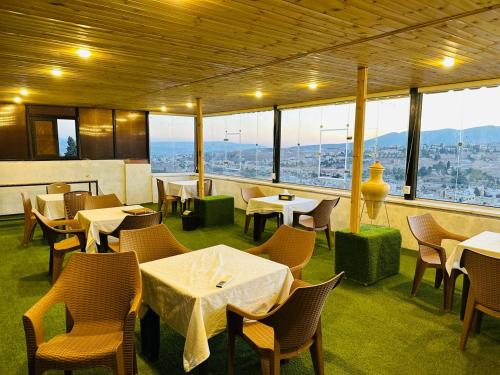 杰拉什Dream house hotel jerash的餐厅设有桌椅和大窗户。