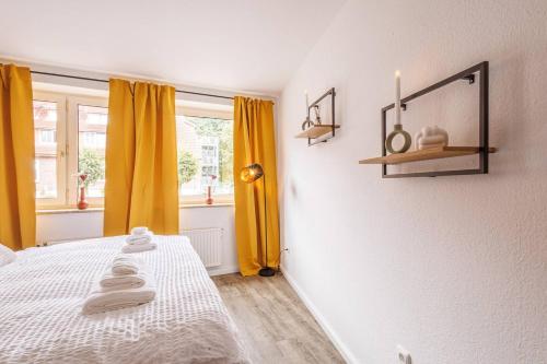 施塔德Traumhaftes Domizil mit Tiefgarage的一间卧室配有黄色窗帘和一张带毛巾的床