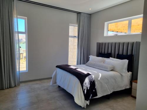 克拉伦斯Villa 206 Clarens Golf Estate的一间卧室设有一张床和两个窗户。