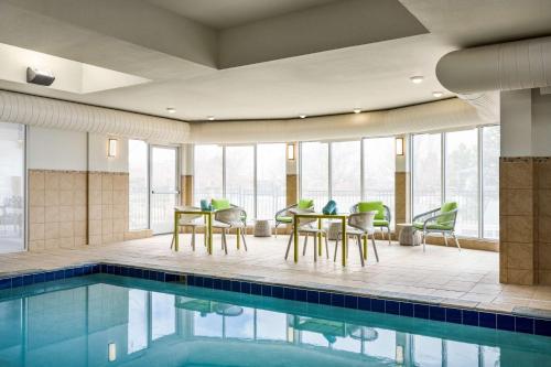 柯林斯堡Hilton Garden Inn Fort Collins的一个带桌椅的游泳池,毗邻带窗户的房间