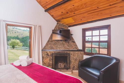 蒙特韦尔迪Chales Boa Vista的一间卧室设有壁炉和一张带椅子的床。