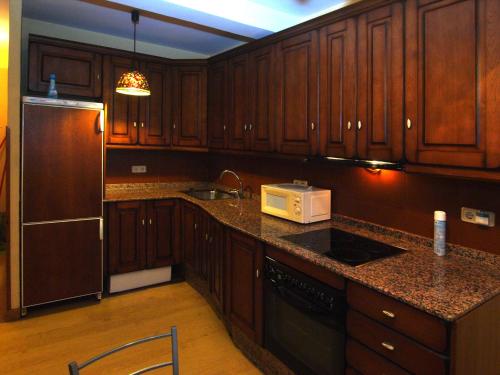 坎加斯-德奥尼斯市政厅广场旅馆的厨房配有木制橱柜和带微波炉的台面。
