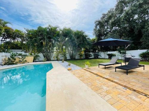劳德代尔堡Tropical Oasis House Private Pool Family Yard的一个带两把椅子和遮阳伞的游泳池