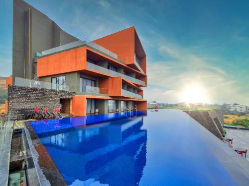 纳西克Aria Resort & Spa的一座带游泳池的建筑的 ⁇ 染