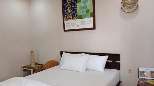 PasarbaruHomestay Suryati Tanjong Tinggi的一间卧室配有一张带白色床单的床和墙上的时钟。