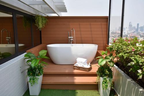 曼谷Grand China Bangkok的浴缸位于植物阳台