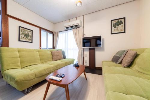 东京Honmachi House的客厅配有两张绿色沙发和一张咖啡桌