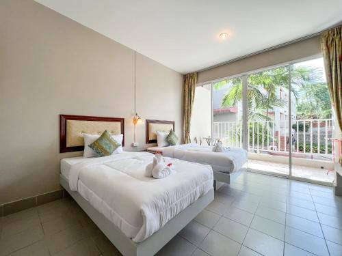 卡塔海滩Tri's Miracle Kata Beach Side的一间卧室设有两张床和大窗户