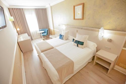 索里亚阿方索八世酒店的酒店客房设有一张白色大床和椅子