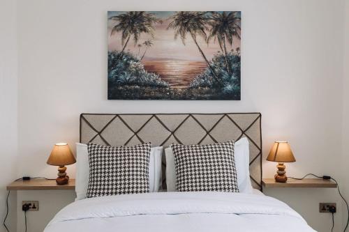 东勒贡Adrich Properties East Legon的一间卧室配有一张带两盏灯的床,墙上挂有一幅画