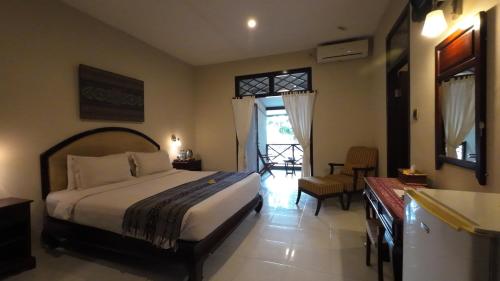 大松巴哇塞马沃过渡酒店的一间卧室配有一张床铺和一张桌子,还设有一间厨房