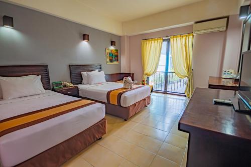 登巴萨Grand Santhi Hotel的酒店客房配有两张床和一张书桌