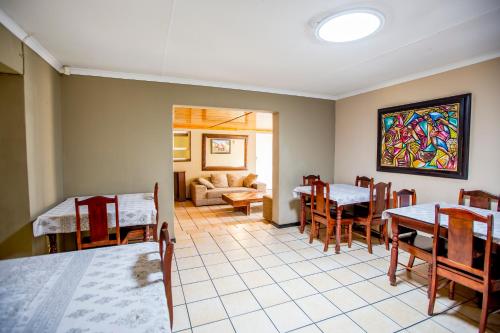开普敦Oria Lodge的用餐室配有桌椅,墙上挂有绘画作品