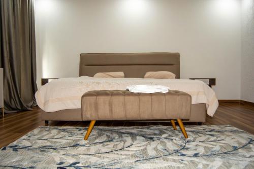 卢萨卡Ista Villa的一间卧室配有一张带搁脚凳和地毯的床