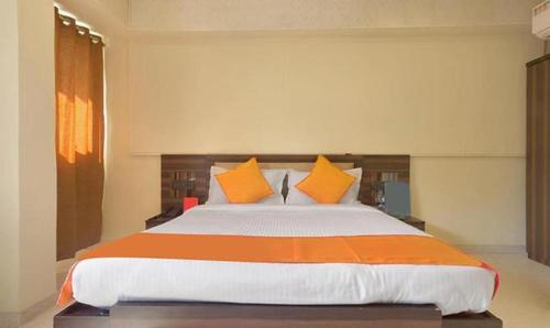 浦那FabHotel Gargi Suites Shivajinagar的一间卧室配有一张带橙色和白色枕头的大床