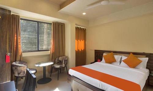 浦那FabHotel Gargi Suites Shivajinagar的配有一张床、一张书桌和一扇窗户的酒店客房