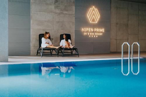 格武霍瓦济Aspen Prime Ski & Bike Resort - basen, sauna, jacuzzi, siłownia w cenie pobytu的两个女人坐在游泳池旁的椅子上