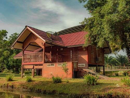 Pattani巴卡兰农场度假村的河边的木房子,有红色屋顶