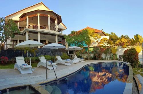 乌明亚Villa Lilly Sea View Pool Villa的一座房子,设有一座带椅子和遮阳伞的游泳池