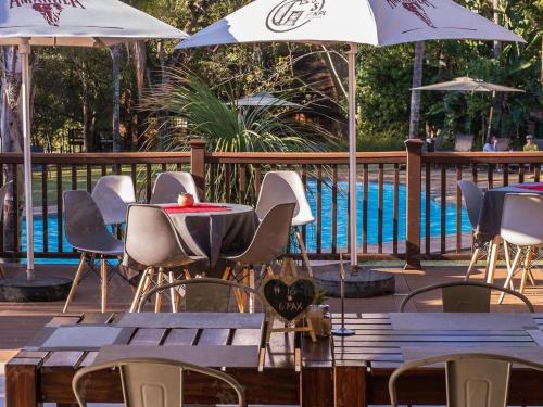 雾观Kruger Park Lodge Unit 531 - PMP的一组桌椅,在游泳池旁边配有遮阳伞