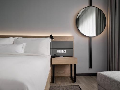 关丹AC Hotel by Marriott Kuantan的卧室配有一张床,墙上设有镜子