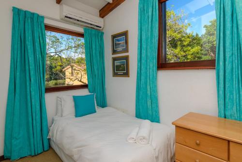 绍斯布鲁姆San Lameer Villa 2017 - 3 Bedroom Standard - 6 pax - San Lameer Rental Agency的一间卧室配有蓝色窗帘、一张床和一张书桌