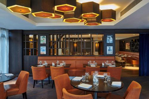 伦敦伦敦伊林希尔顿逸林酒店的一间带桌椅和吊灯的餐厅