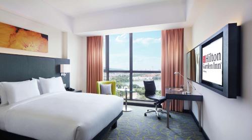 普崇Hilton Garden Inn Puchong的酒店客房配有一张床、一张书桌和一台电视。