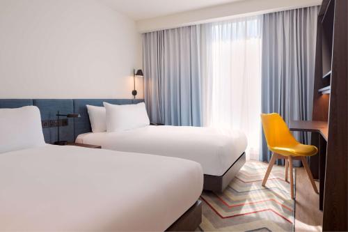 阿什福德Hampton by Hilton Ashford International的酒店客房,设有两张床和一张黄色椅子