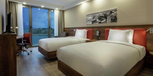 盖利博卢Hampton by Hilton Canakkale Gelibolu的酒店客房设有两张床、一张桌子和一台电视。