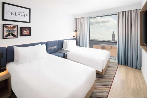 罗奇代尔Hampton By Hilton Rochdale的酒店客房设有两张床和窗户。