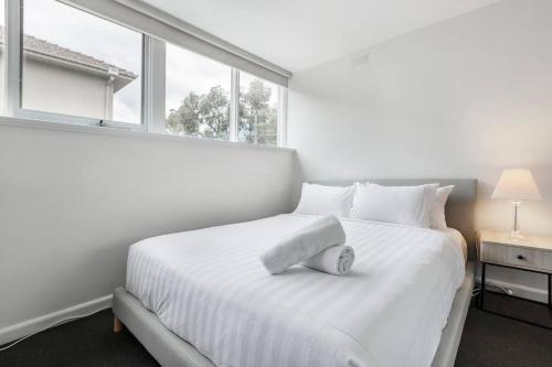 墨尔本Bright and Modern Space with a Balcony and Parking的白色卧室设有白色的床和窗户
