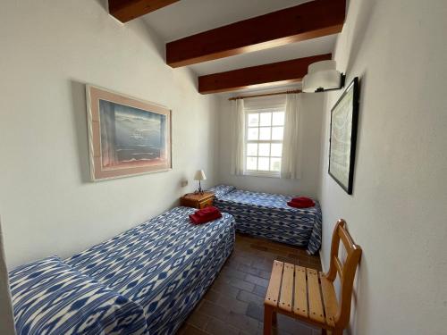 福尔内利斯ES CASTELL 1 by SOM Menorca的一间卧室设有两张床、一把椅子和一个窗户。