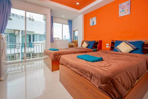 芭东海滩Nice to meat you Rooms的橙色墙壁的客房内的两张床
