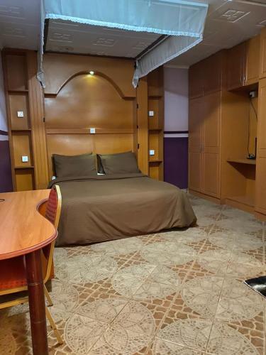 KimanaPenuel Plaza Hotel的一间卧室配有一张带木制床头板和一张桌子的床。