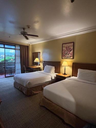 碧瑶Private Unit at The Camp John Hay Manor的酒店客房设有两张床和窗户。