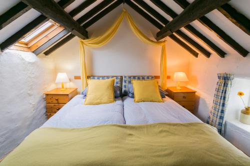 RhoscolynCyndal Bach的一间卧室配有两张带黄色枕头的床