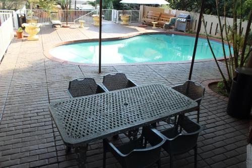 比勒陀利亚紫橄榄宾馆的游泳池前的桌椅