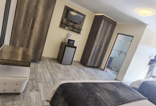 比勒陀利亚Lasev Resort的卧室配有一张床,墙上配有电视。