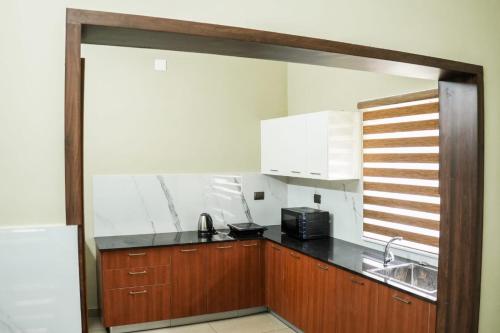 阿勒皮Zennova Furnished Apartment的厨房配有木制橱柜、水槽和微波炉