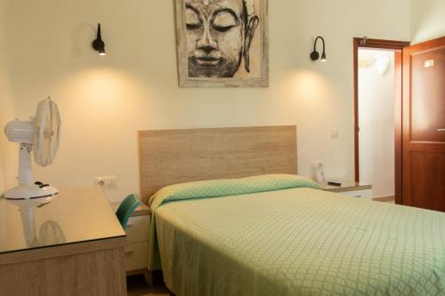 卡门港Hostal Magec的卧室配有一张床,墙上挂有绘画作品