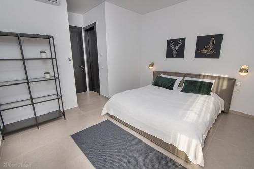 哈德拉Architect beach house的卧室配有带绿色枕头的大型白色床