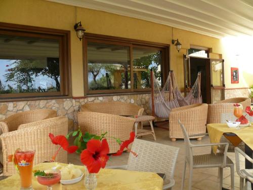 兰佩杜萨Alba D'Amore Hotel & Spa的餐厅设有桌椅,并配以红色的鲜花