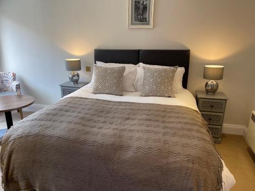 库克姆The Crown of Cookham的一间卧室配有一张大床、两张桌子和两盏灯。