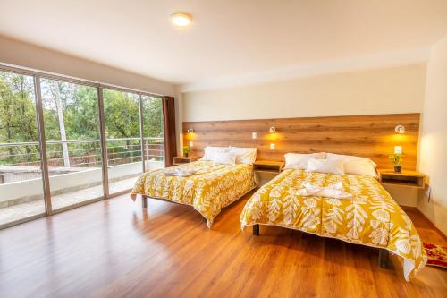 乌鲁班巴Valles Apartamentos Ecológicos VAE - Urubamba Cusco Perú的一间卧室设有两张床和大窗户