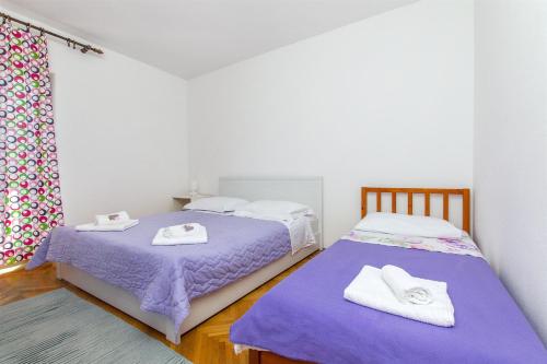 杜埃Apartment Jordan的配有两张床铺的宿舍间提供紫色床单和毛巾