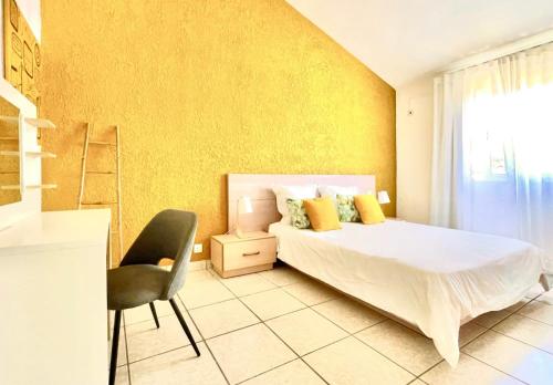 弗利康弗拉克Azur - Résidence Le Dattier的一间卧室配有一张床、一把椅子和黄色的墙壁