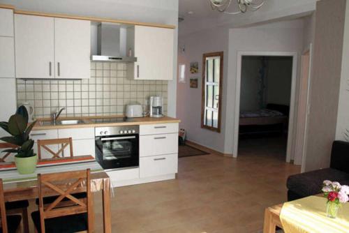 萨加尔德Ferienhaus Frieda的厨房配有白色橱柜、桌子和用餐室。