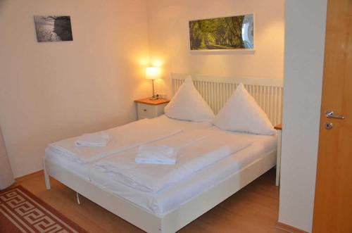 萨斯尼茨Fürstenhof - Ferienwohnung 403的一间卧室配有带白色床单和枕头的床。