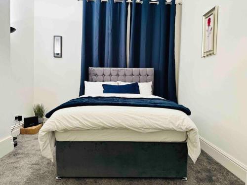 德比Bespoke 2 Bedroom Apt Derby City的一间卧室配有一张带蓝色窗帘的大床